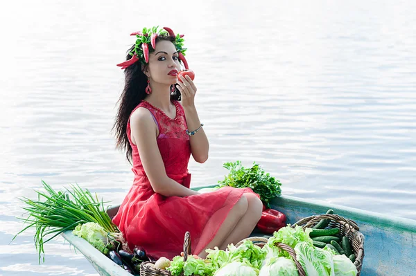 Kvinna på båten med grönsaker äter tomater — Stockfoto