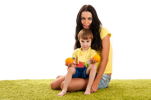 Mutter und Sohn sitzen auf dem grünen Gras mit Orangen — Stockfoto