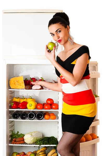 Mooie vrouw in jurk staande op de koelkast — Stockfoto