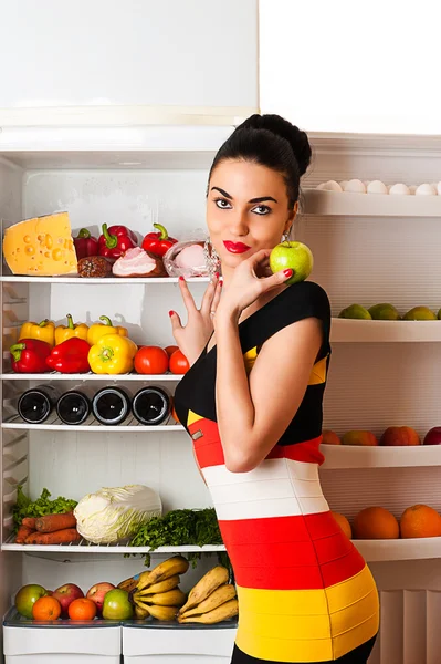 Attractive woman in dress standing at the fridge — Stock Photo, Image