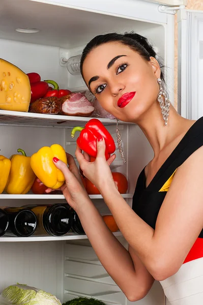 Beautiful woman takes peppers from the fridge — Stock Photo, Image