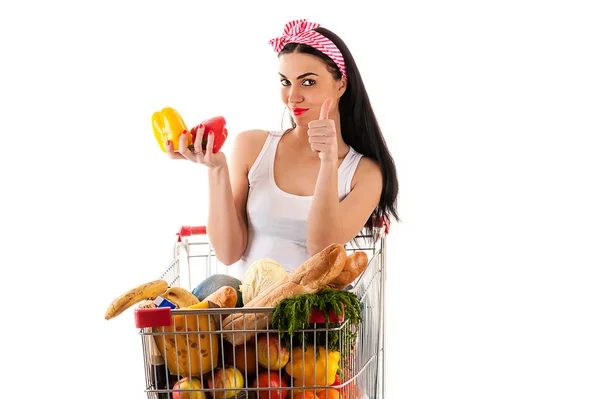 Beautiful woman sitting in supermarket trolley with pepper — Stock Photo, Image