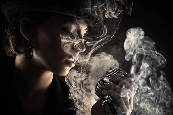 Laulaja nainen retro mikrofoni savussa — kuvapankkivalokuva
