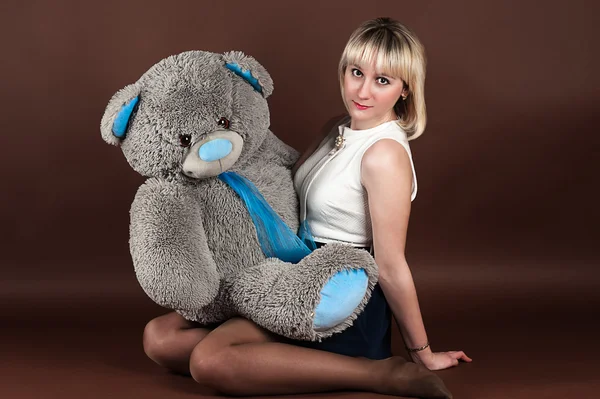 Frau umarmt einen Teddybär isoliert auf einem braunen — Stockfoto