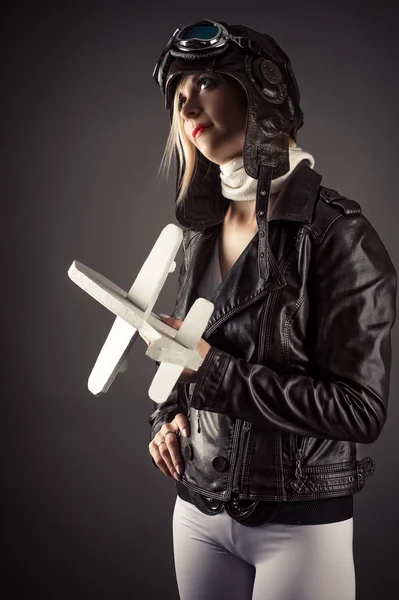 Woman in aviator hat standing with toy airplane in hand — 图库照片