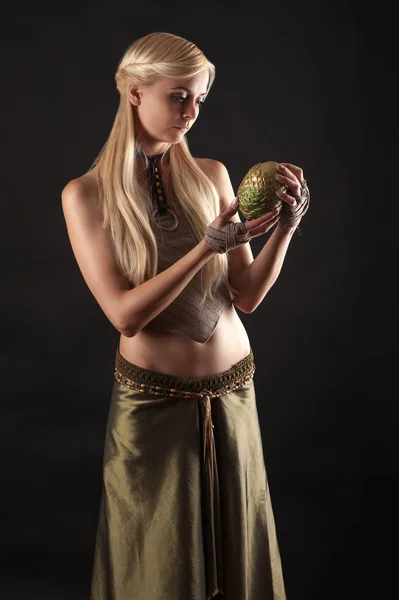 Beautiful woman in dress holding a dragon egg in hands — Stock Photo, Image