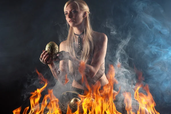 Beautiful woman with a nest egg dragons in the fire — Stock Photo, Image