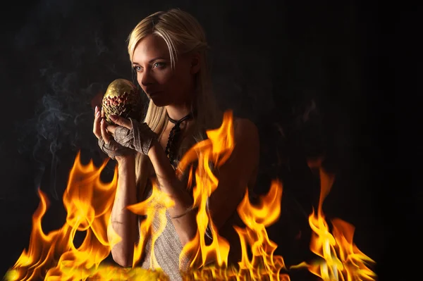 Pensive woman with a dragon egg in the fire — Stock Photo, Image