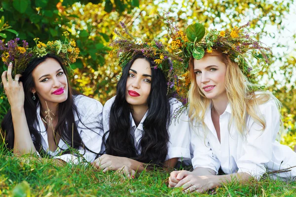 Tres encantadora mujer acostada en la hierba con corona de flores en la cabeza — Foto de Stock