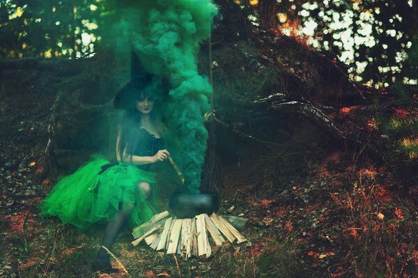 Woman witch in the forest preparing a potion in a cauldron on nature