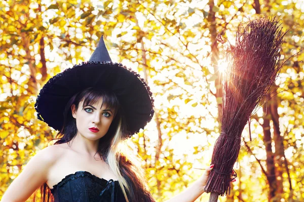 Piękna kobieta w obraz czarownicy z kapelusz i miotły — Zdjęcie stockowe