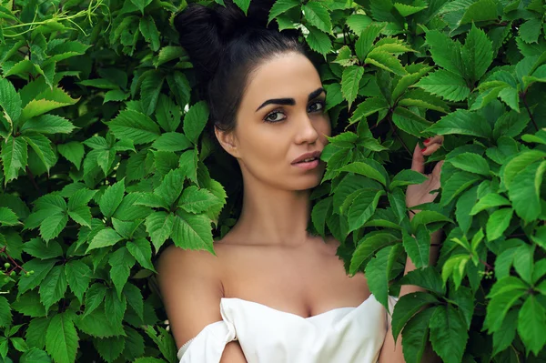 Mulher sedutora com penteado luxuoso em folhas verdes — Fotografia de Stock