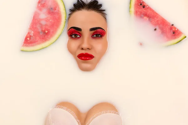 Charmante Frau liegt in Milch mit Scheiben Wassermelone — Stockfoto