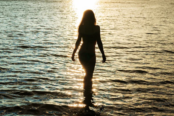 Temná silueta ženy při západu slunce ve vodě — Stock fotografie