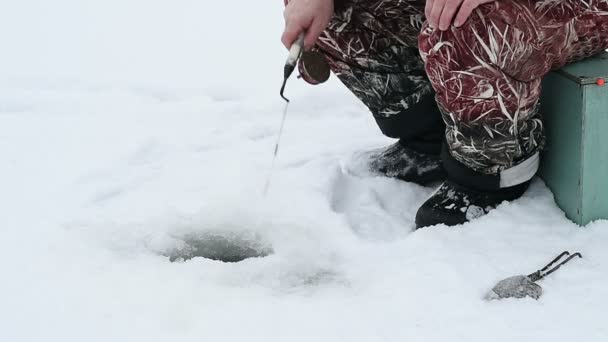 Человек рыбалка в яме зимой — стоковое видео