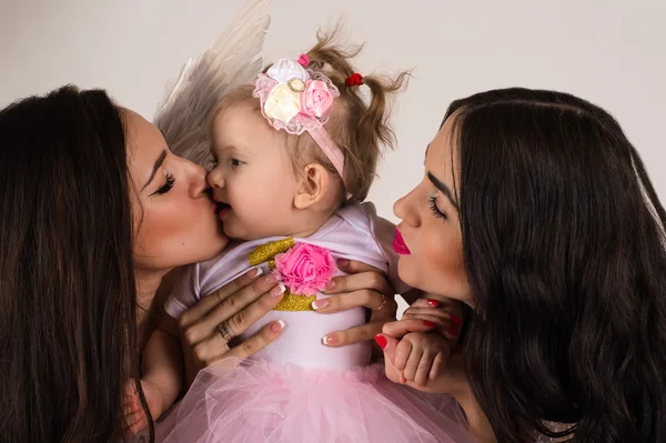 Two beautiful angels kissing little baby — Stock Photo, Image