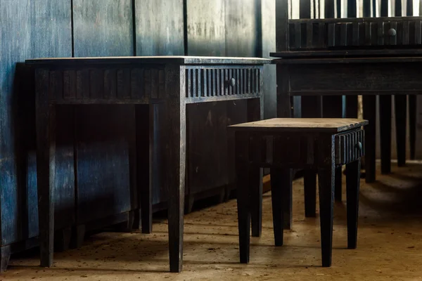 Gamla trä skrivbord i ett mörklagt rum belyses med ljus från th — Stockfoto