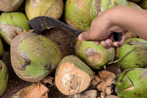 Mann zerhackt Kokosnuss mit Messer zum Kochen. — Stockfoto
