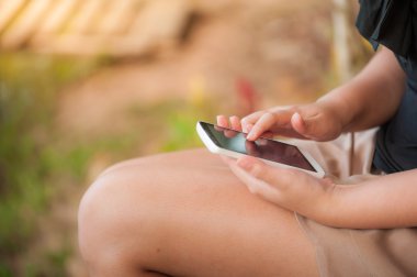 Parkta akıllı telefon kullanan genç kadın.