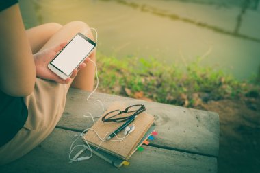 Parkta akıllı telefon kullanan genç kadın.