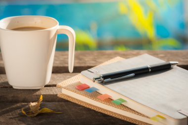 Rustik ahşap masa üstünde defter ile kahve fincanı