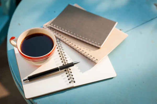 Notenook en koffie cup op houten tafel — Stockfoto