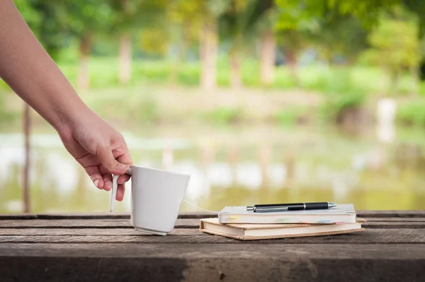 Xícara de café com notebook sobre mesa de madeira rústica — Fotografia de Stock