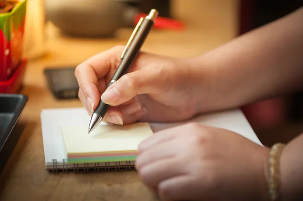 Female hand writing on notepad — Stock Photo, Image