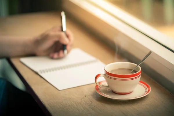 Запись на ноутбуке с чашкой кофе — стоковое фото