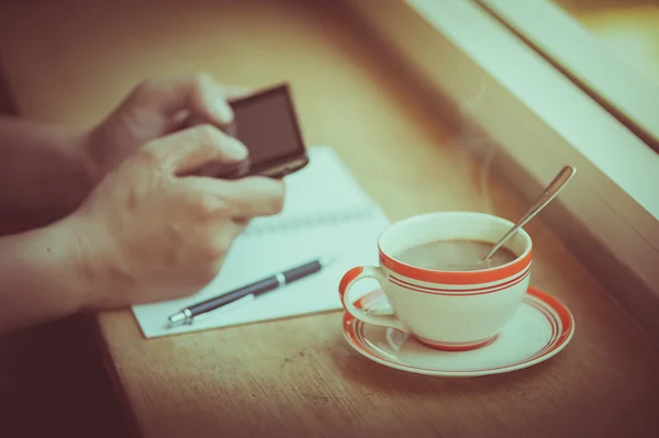 Smartphone mit Kaffeetasse nutzen — Stockfoto