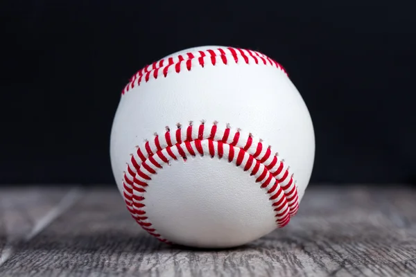 Baseball su una superficie di legno su uno sfondo nero . — Foto Stock