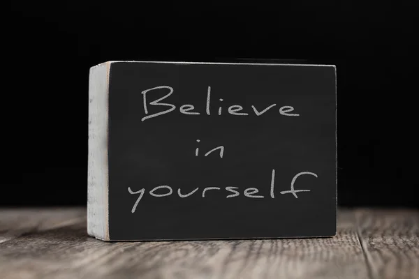 Chalkboard on a wood surface against a black background - Believe in Yourself — Stock Photo, Image