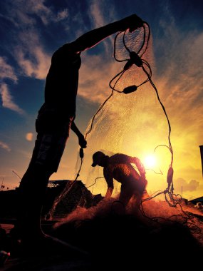 Vietnamlı balıkçılar gün batımında balık ağları hazırlıyorlar.