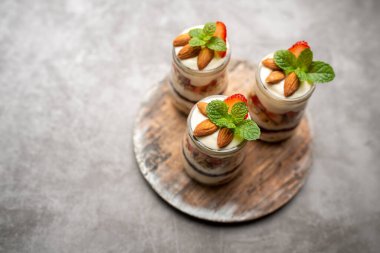 Çilekli tatlı kavanozu, üzerinde badem olan yoğurt meyveli parfe.