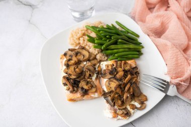 Sade Yunan yoğurdu ve mantarla kaplı, kahverengi pirinç ve yeşil fasulyeli somon yemeği..