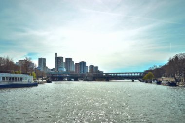 Paris rıhtımının manzarası, büyük bir köprü, tekneler ve nehir boyunca sakin kentsel yaşam..