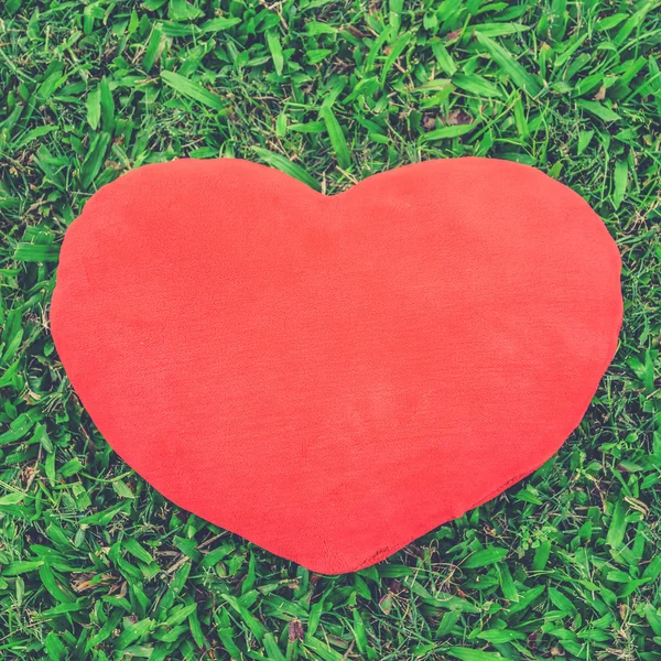 Big love heart shape pillow on green grass (Vintage filter effec — Stock Photo, Image