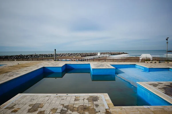 Half filled swimming pool with dirty water at closed empty beach during quarantine in Mar del Plata, Argentina.