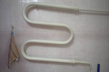 Banyoda duvardaki ısıtıcı borusu. Eski Sovyet dairesinde havlu kurutma borusu. Banyo içi fayanslı duvarla kaplı..