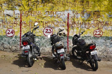 Kanyakumari, Tamil Nadu, Hindistan - Şubat 2017: Sarı duvarın yanındaki otoparka park edilmiş üç motosiklet