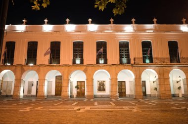 Cordoba, Arjantin - Ocak 2020: Cabildo de Cordoba adlı belediye binasının bir kısmı gece aydınlatma ve rüzgarda sallanan Arjantin bayraklarıyla. Kemer yolu olan eski tarihi bina.