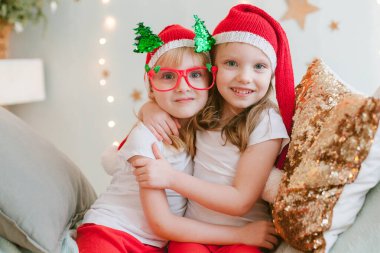 Noel Baba şapkalı iki mutlu küçük kız. Noel zamanı. Yeni yıl 2021. Kız kardeşler eğleniyor.