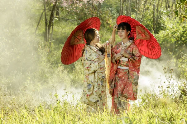 İki Asyalı kadınlar geleneksel Japon kimono ve kırmızı u
