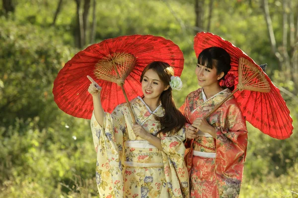 Pareja asiática mujeres usando tradicional japonés kimono y rojo u Imágenes de stock libres de derechos