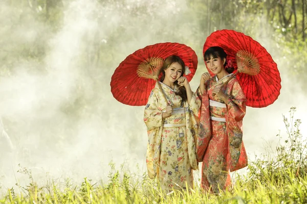 Pareja asiática mujeres usando tradicional japonés kimono y rojo u Fotos de stock