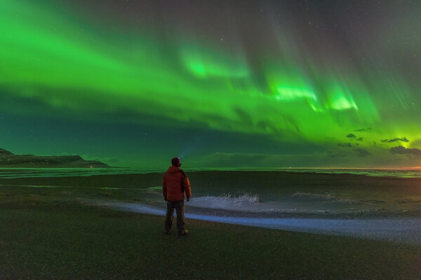 Incredible bright northern lights dancing above the floating icebergs of Jokulsarlon lagoon during setting Moon.