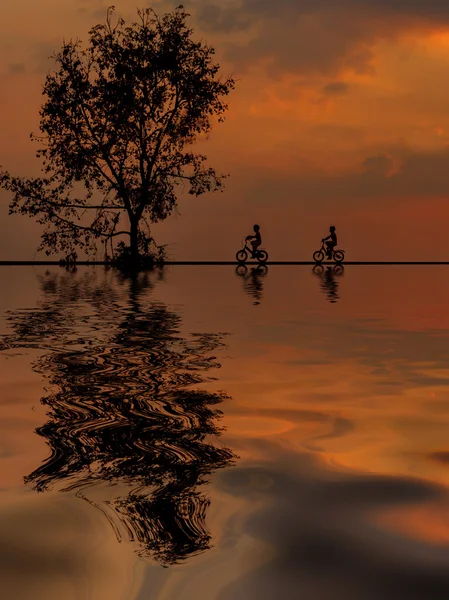 Sunrise iki dağ bisikletçinin siluet su yansıması ile