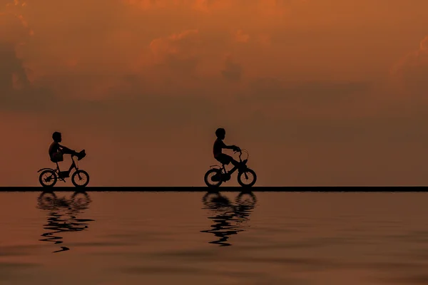 Sunrise iki dağ bisikletçinin siluet su yansıması ile