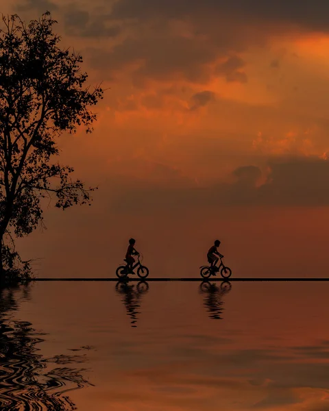 Sunrise iki dağ bisikletçinin siluet su yansıması ile