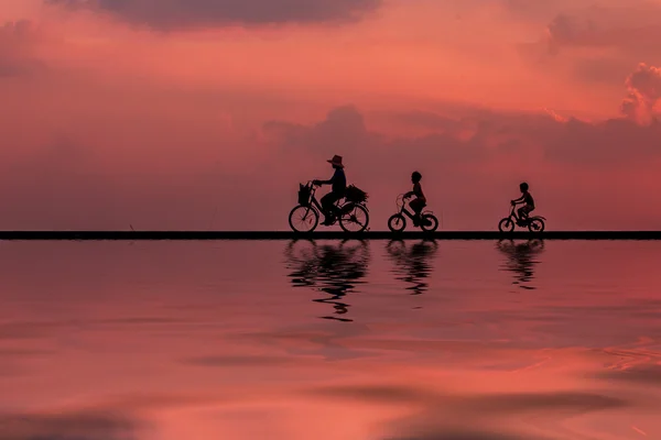 Drzewo rowerzysta sylwetka w sunrise z odbiciem w wodzie — Zdjęcie stockowe
